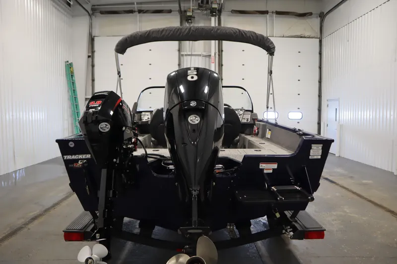 Slide: The Image of 2023 Tracker Pro Guide V-175 WT boat in a garage, rear view with dual engines. - 6