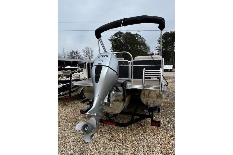 Slide: The Image of 2019 Manitou 23 Aurora LE Standard pontoon boat with outboard motor, parked on gravel. - 3