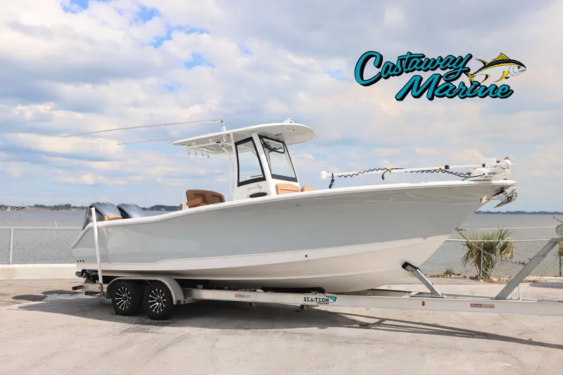 The Image of 2022 Sea Hunt Gamefish 27 boat on trailer, coastal background, Castaway Marine logo. - 0