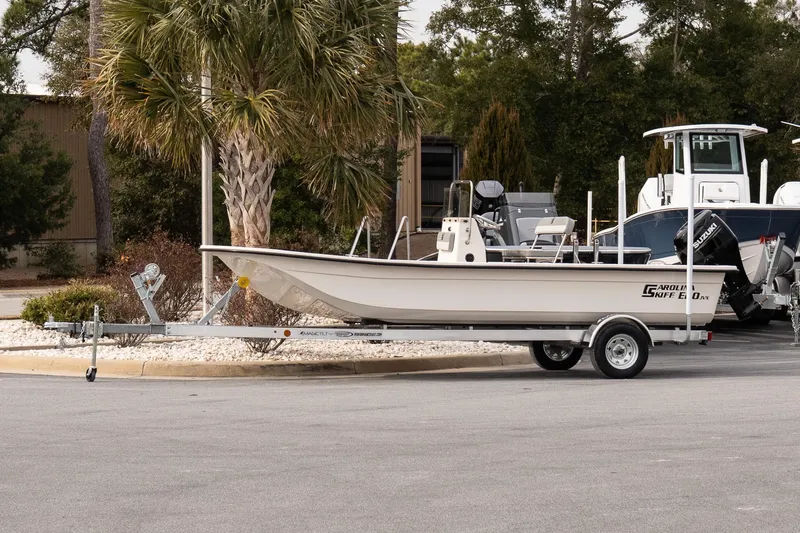 The Image of 2026 Carolina Skiff E20 JVX CC boat on trailer, parked near palm trees. - 1