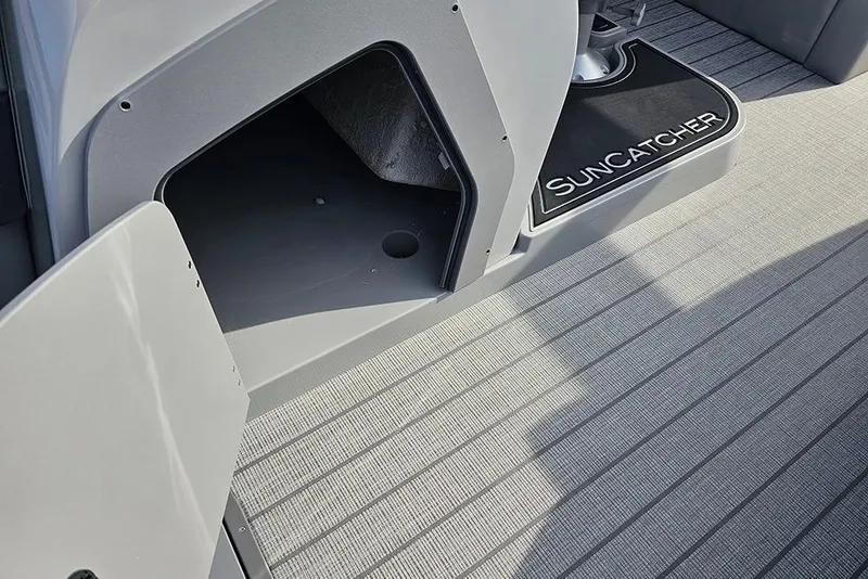 Slide: The Image of 2026 SunCatcher Fusion 324SS boat interior with open storage compartment and branded mat. - 22
