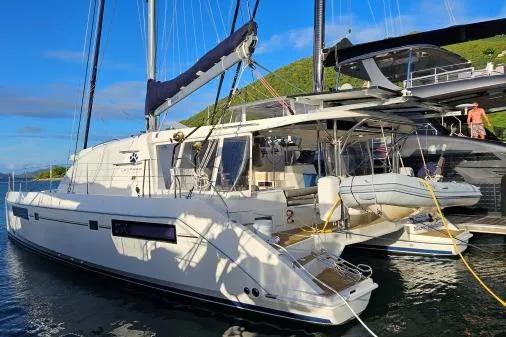 Slide: The Image of 2015 Leopard 48 catamaran docked in a scenic marina, featuring modern design and spacious deck. - 2