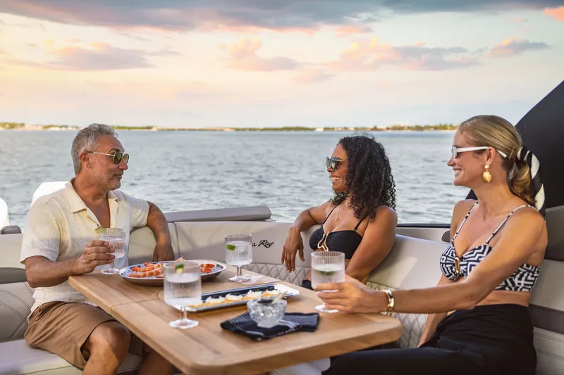 Slide: The Image of Three people enjoy drinks and snacks on a Sea Ray SLX 360 Outboard boat at sunset. - 7