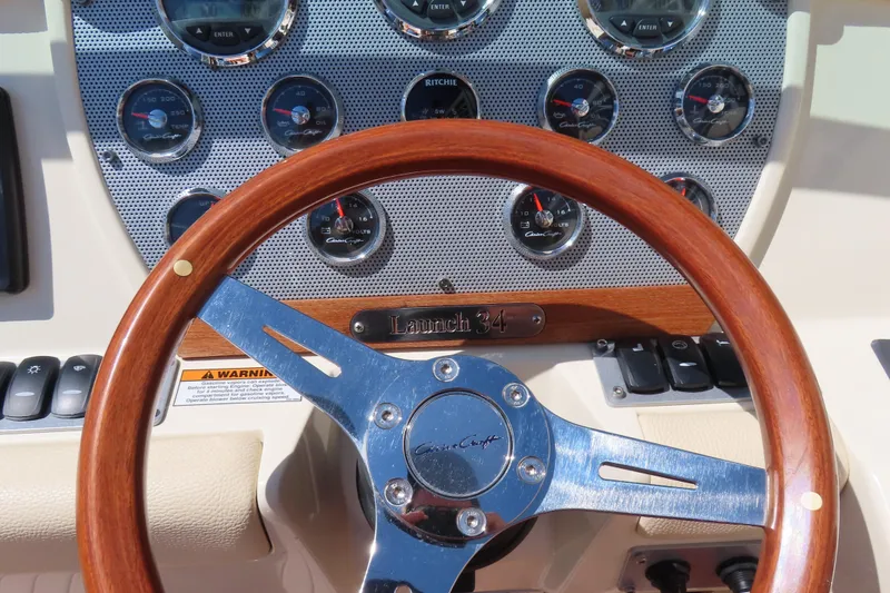 Slide: The Image of 2018 Chris Craft Launch 34 dashboard with wooden steering wheel and gauges. - 32