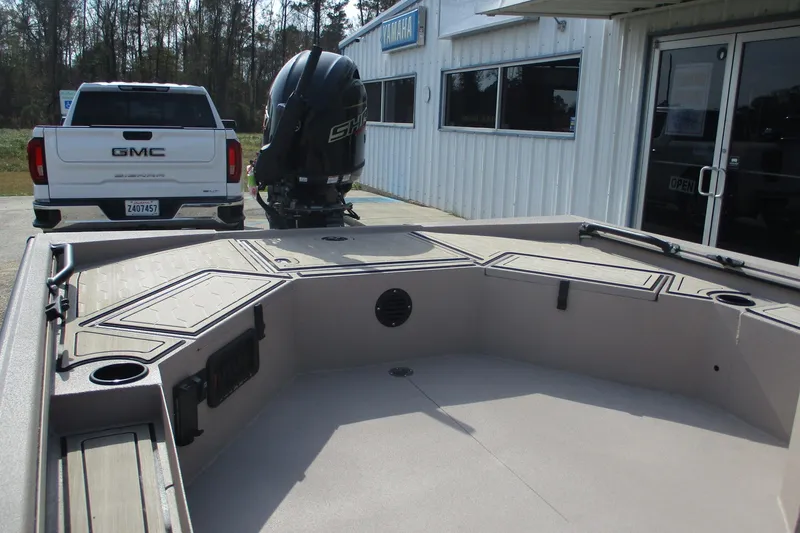 Slide: The Image of 2026 Avid 18 Commander boat interior with storage compartments, parked near a GMC truck. - 10