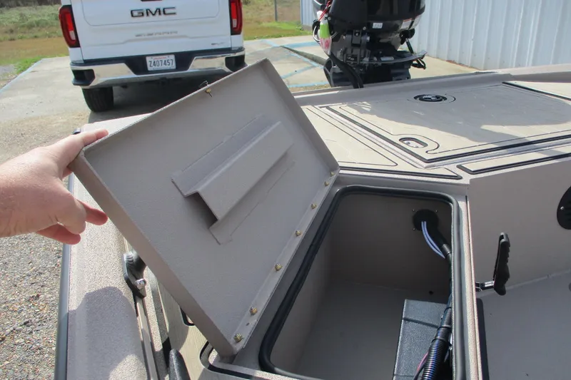 Slide: The Image of Open storage compartment on 2026 Avid 18 Commander boat, with a GMC truck in the background. - 9
