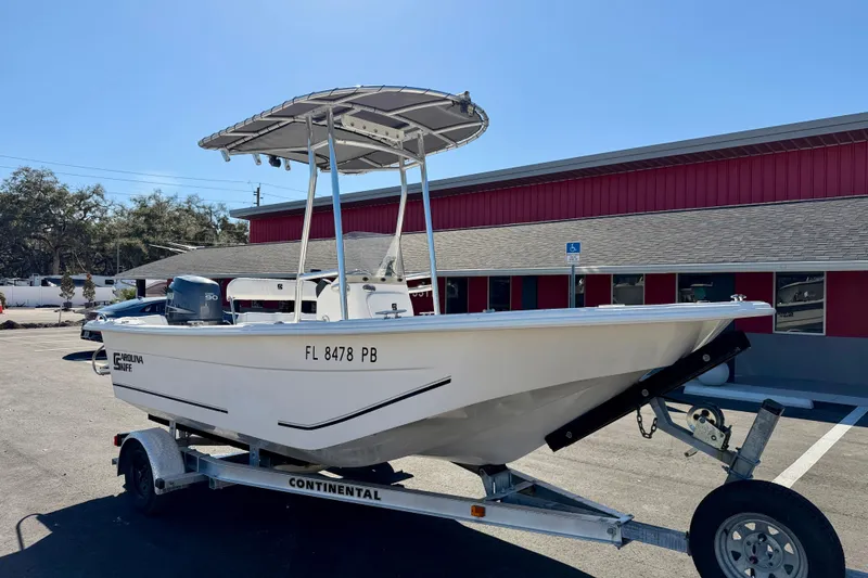 Slide: The Image of 2010 Carolina Skiff 192 DLV boat on trailer, parked outside a red building. - 4