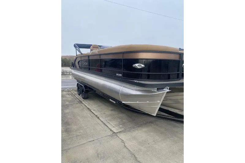 The Image of 2026 Manitou 25 Encore RF VPII pontoon boat on trailer, side view. - 1