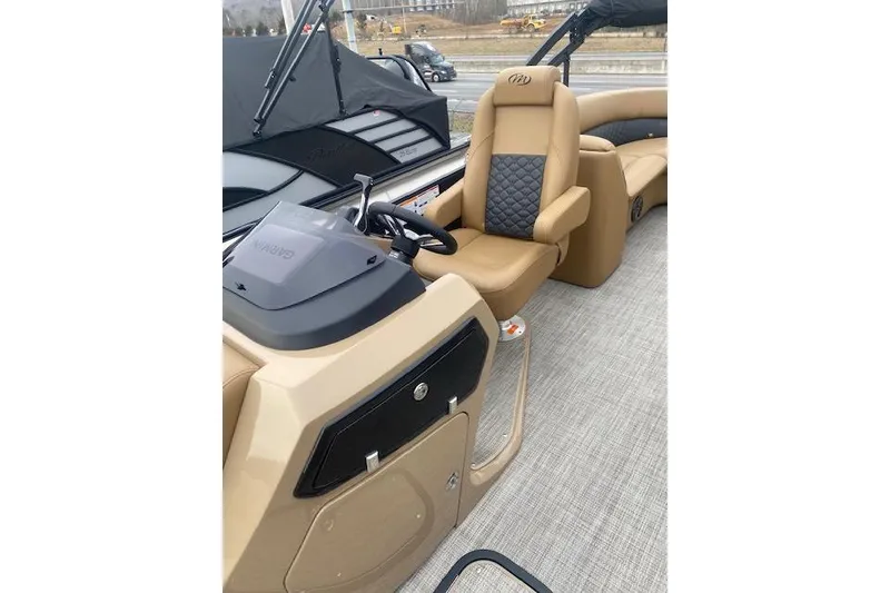 Slide: The Image of 2026 Manitou 25 Encore RF VPII boat interior with tan seating and steering console. - 10