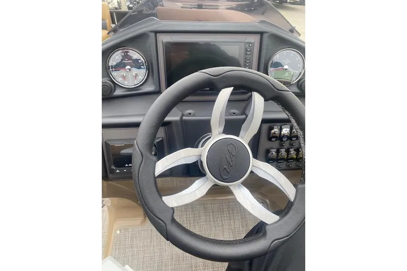 Slide: The Image of Steering wheel of 2026 Manitou 25 Encore RF VPII boat, featuring modern dashboard controls. - 14
