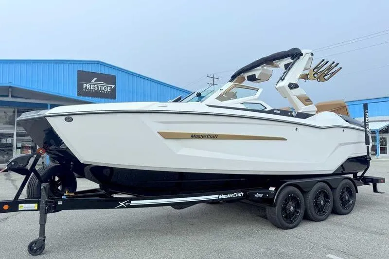 Slide: The Image of 2026 MasterCraft X24 boat on trailer outside Prestige dealership. - 7
