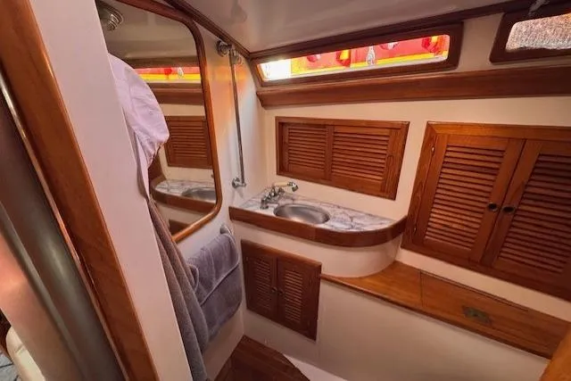 Slide: The Image of 1986 Fairweather Mariner 39 yacht bathroom with wooden cabinets and marble countertop. - 11