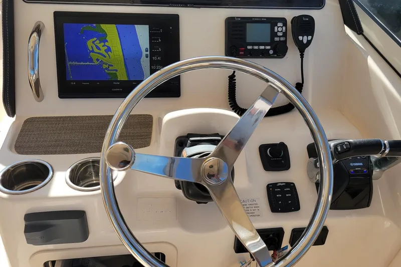 Slide: The Image of 2019 Grady-White Freedom 307 boat dashboard with steering wheel and navigation equipment. - 15