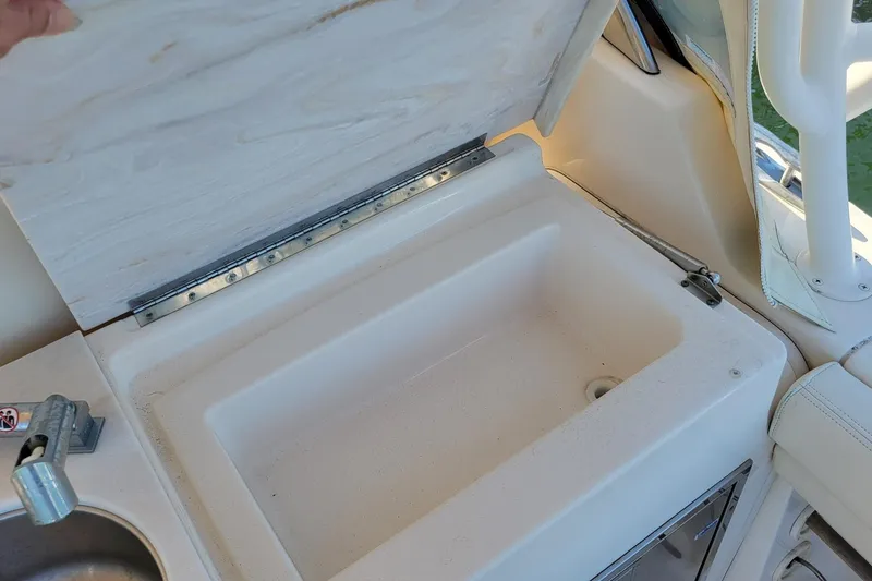 Slide: The Image of 2019 Grady-White Freedom 307 boat sink with open lid, showcasing storage space. - 7