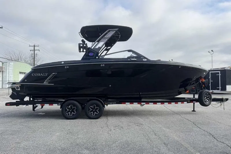 Slide: The Image of 2026 Cobalt R8 Surf boat on trailer, sleek black design, parked outdoors. - 8