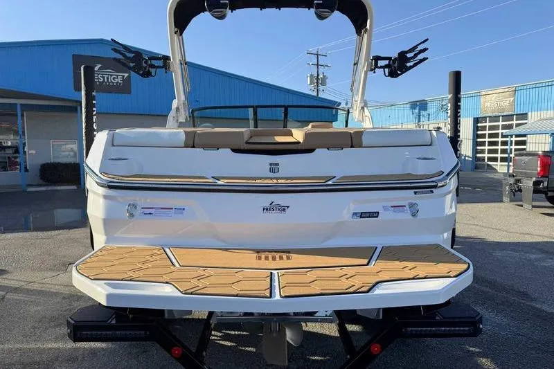 Slide: The Image of 2026 MasterCraft NXT20 boat rear view with teak deck, parked outside dealership. - 12