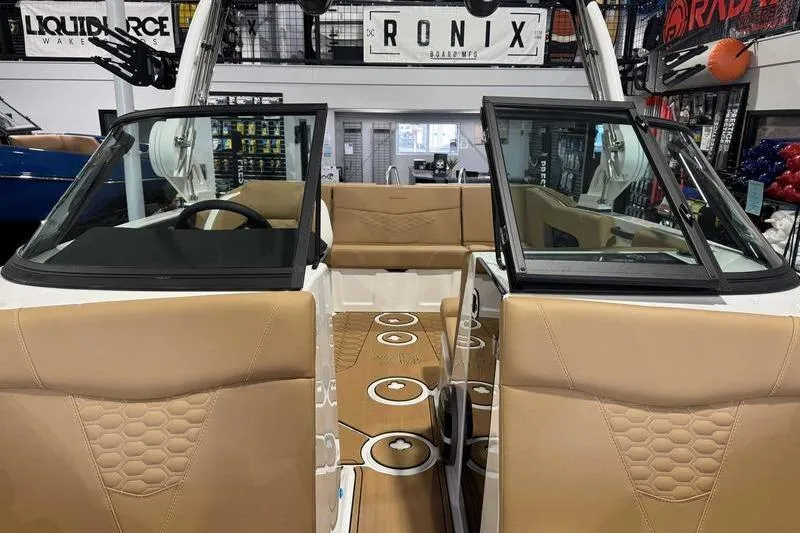 Slide: The Image of 2026 MasterCraft NXT20 boat interior with tan seats and open windshield in showroom. - 14