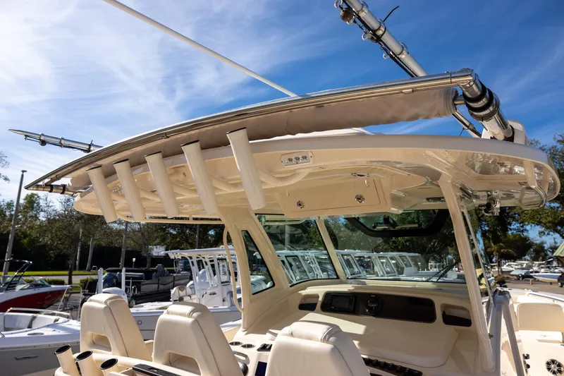 Slide: The Image of 2022 Grady-White Canyon 376 boat with rod holders and helm, under clear blue sky. - 15