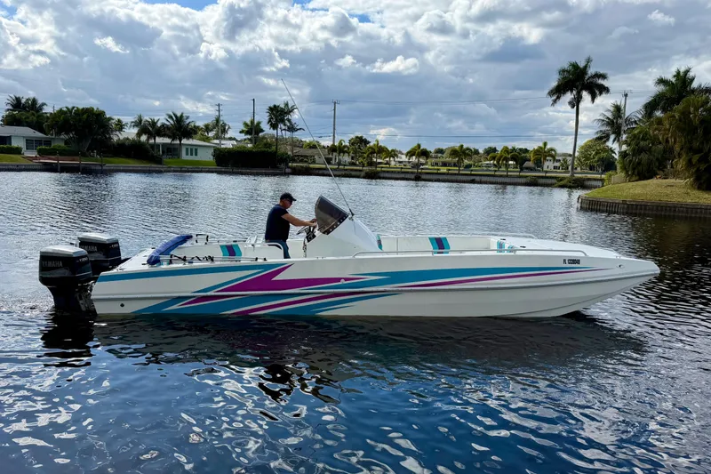 Slide: The Image of 2001 Cobra Predator 3100 boat on a calm waterway, vibrant graphics, palm trees in background. - 13