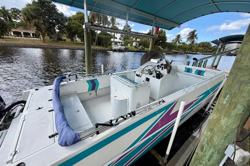 Slide: The Image of 2001 Cobra Predator 3100 boat docked under a canopy on a scenic waterway. - 19