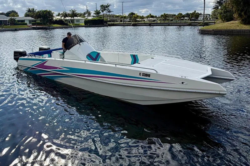 Slide: The Image of 2001 Cobra Predator 3100 boat with vibrant graphics on a calm waterway. - 22