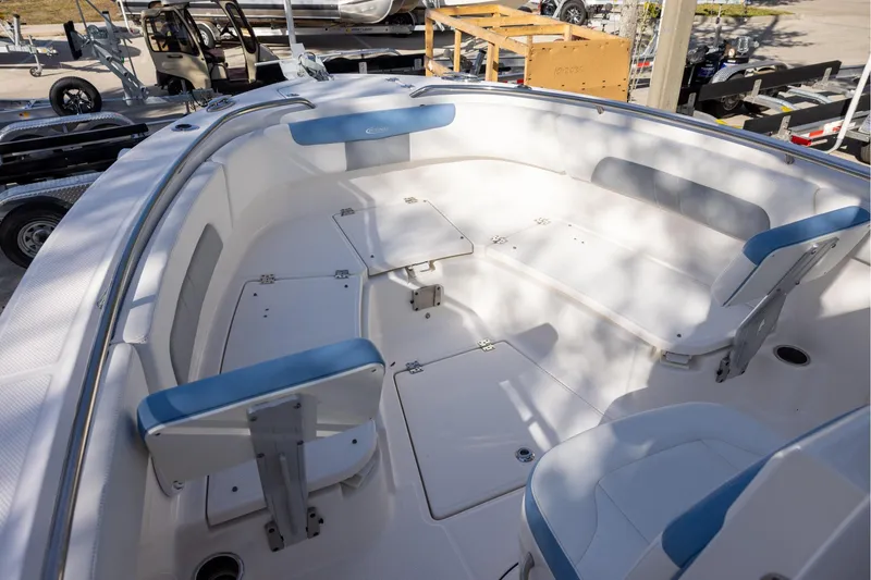 Slide: The Image of 2022 Robalo R242 Explorer boat interior with blue and white seating, docked outdoors. - 13
