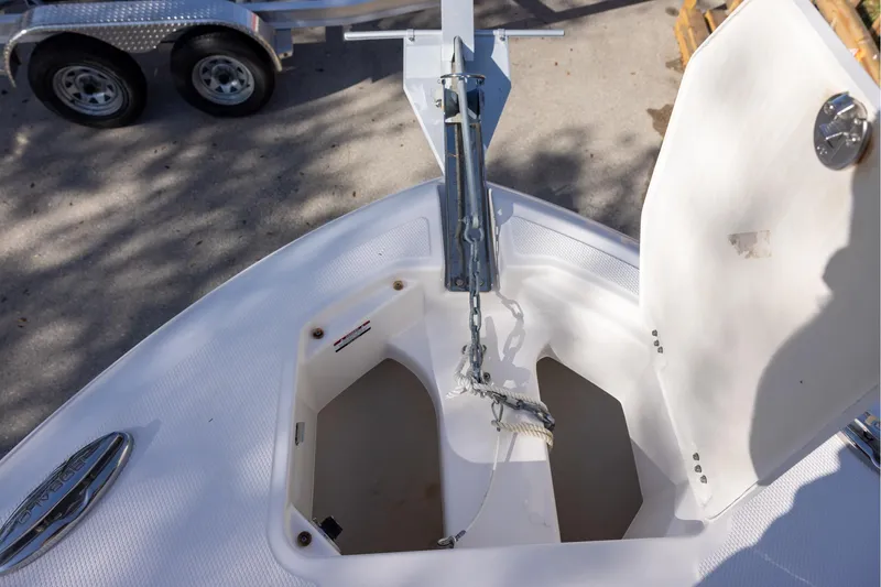 Slide: The Image of 2022 Robalo R242 Explorer anchor compartment with open hatch, showcasing chain and storage. - 14