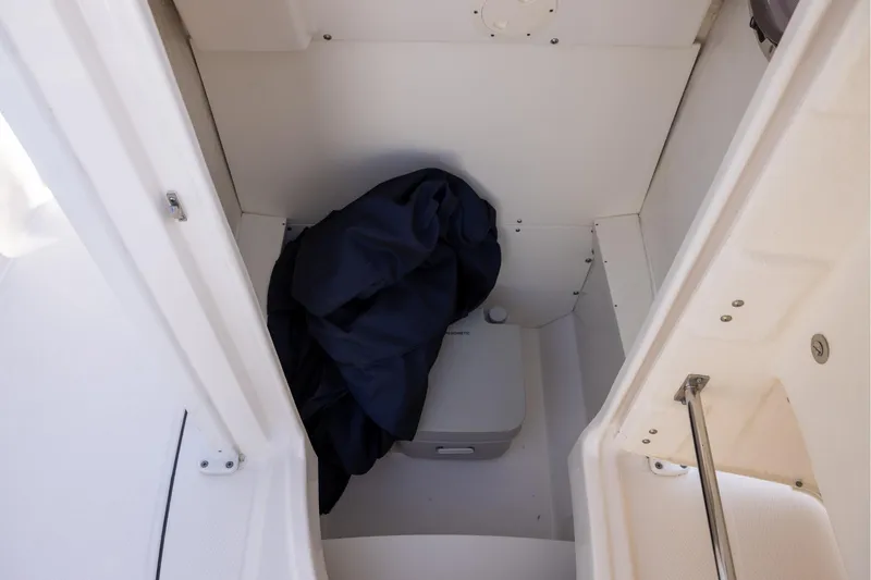 Slide: The Image of 2022 Robalo R242 Explorer interior storage compartment with portable toilet and dark fabric. - 16