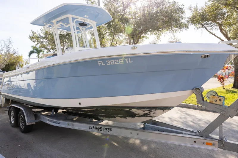 Slide: The Image of 2022 Robalo R242 Explorer boat on trailer, light blue hull, parked outdoors. - 2