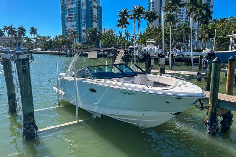 Slide: The Image of 2021 Chaparral 280 OSX boat docked in a marina with palm trees and buildings. - 12
