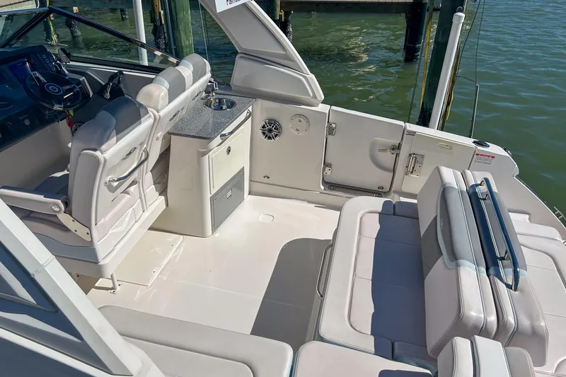 Slide: The Image of 2021 Chaparral 280 OSX boat interior with seating and helm, docked by the water. - 16