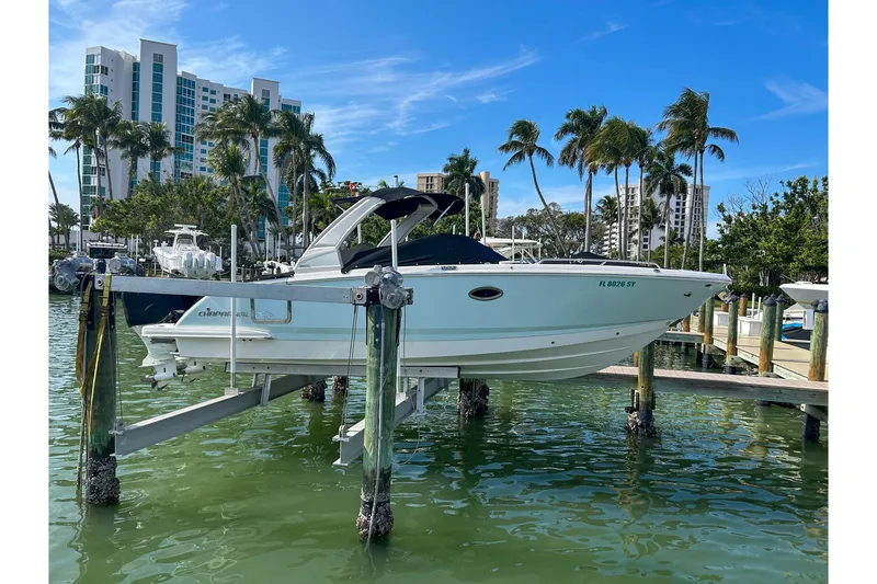 Slide: The Image of 2021 Chaparral 280 OSX boat docked, surrounded by palm trees and modern buildings. - 2