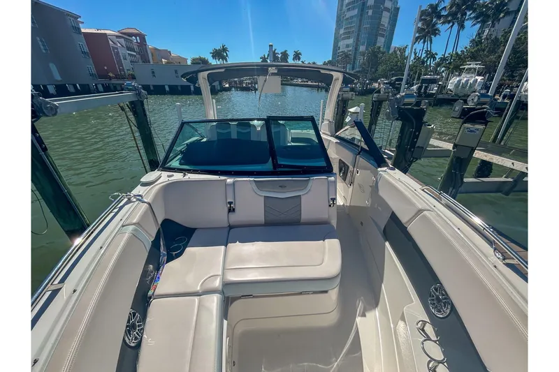 Slide: The Image of 2021 Chaparral 280 OSX boat interior with seating, docked in a sunny marina. - 8