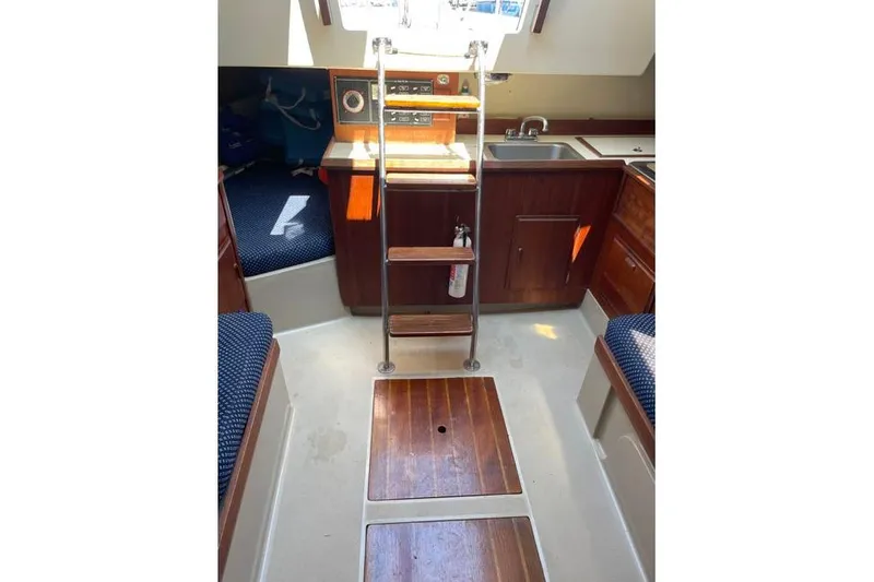 Slide: The Image of 1982 O'Day 28 sailboat interior with wooden steps, kitchenette, and seating area. - 10
