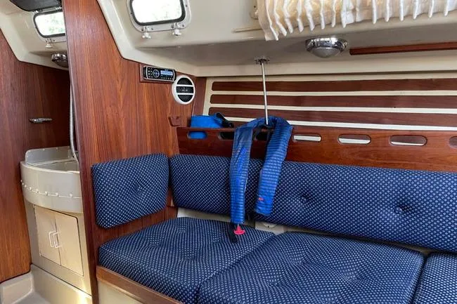 Slide: The Image of Interior of a 1982 O'Day 28 sailboat with blue cushioned seating and wood paneling. - 5
