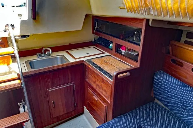 Slide: The Image of 1982 O'Day 28 sailboat interior with wooden cabinetry and compact kitchen area. - 7