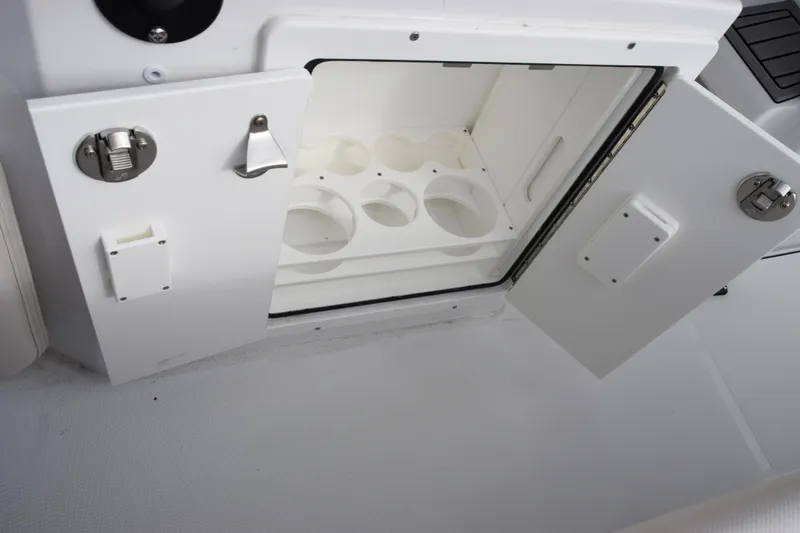 Slide: The Image of Open storage compartment on 2026 Sea Hunt Ultra 245 SE boat, featuring cup holders. - 18