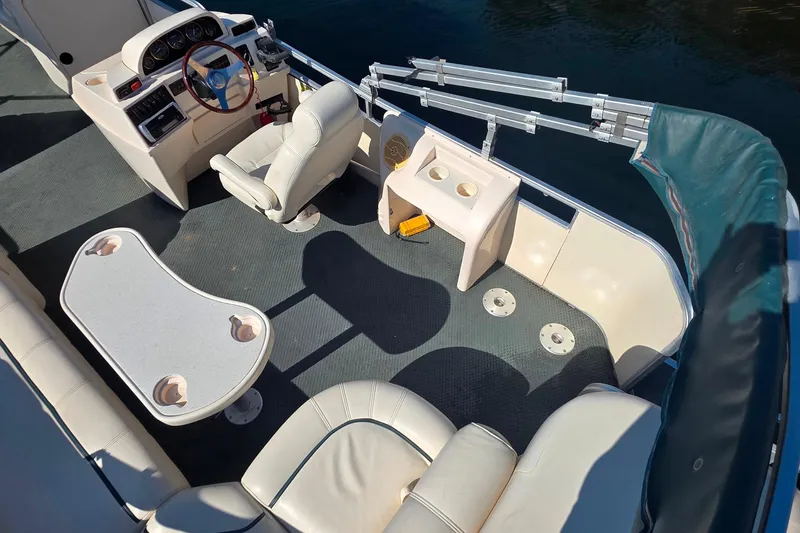 Slide: The Image of 2004 Sanpan 2500 RE pontoon boat interior with seating, table, and steering console. - 2
