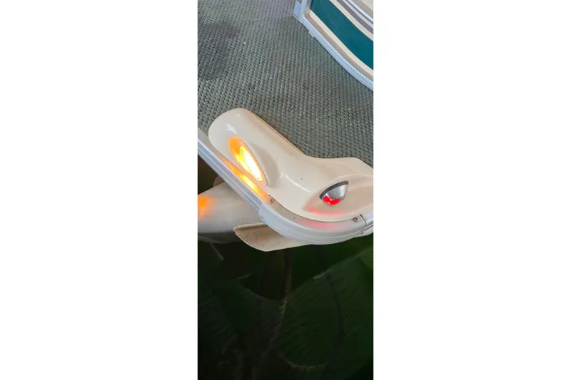 Slide: The Image of 2004 Sanpan 2500 RE pontoon boat interior with seating and helm, on calm water. - 20