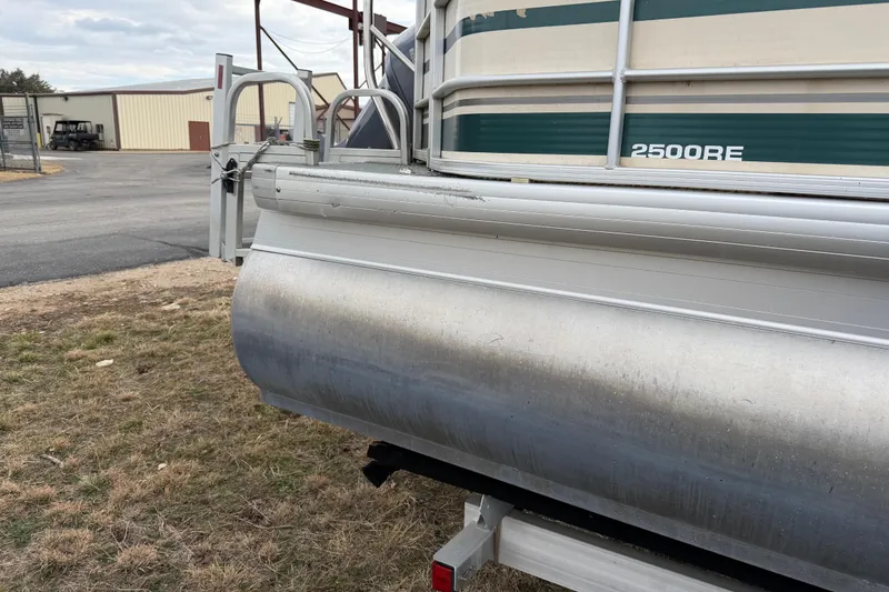 Slide: The Image of 2004 Sanpan 2500 RE pontoon boat, side view, parked on grass near industrial buildings. - 40