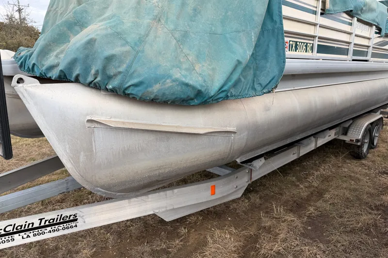 Slide: The Image of 2004 Sanpan 2500 RE pontoon boat on trailer, covered with a green tarp. - 44