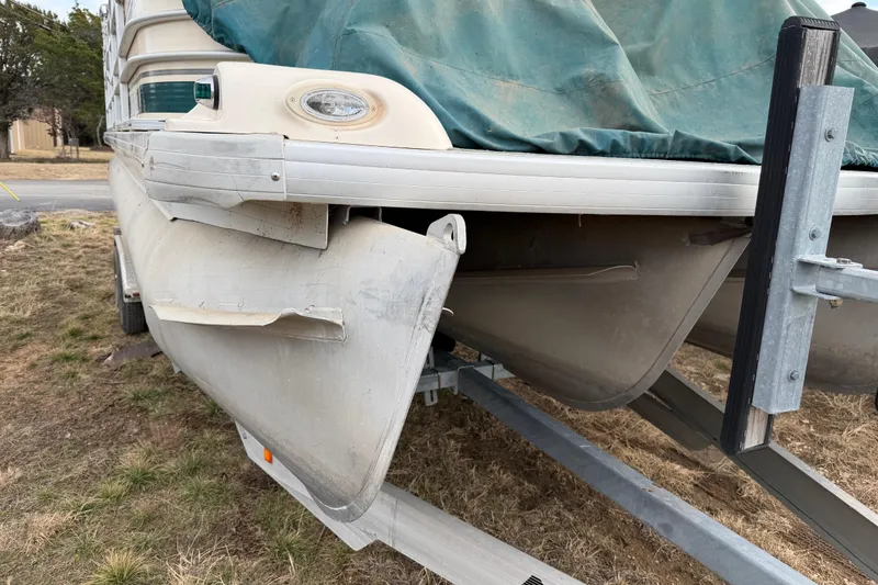 Slide: The Image of Damaged 2004 Sanpan 2500 RE pontoon boat on trailer, covered with green tarp. - 45