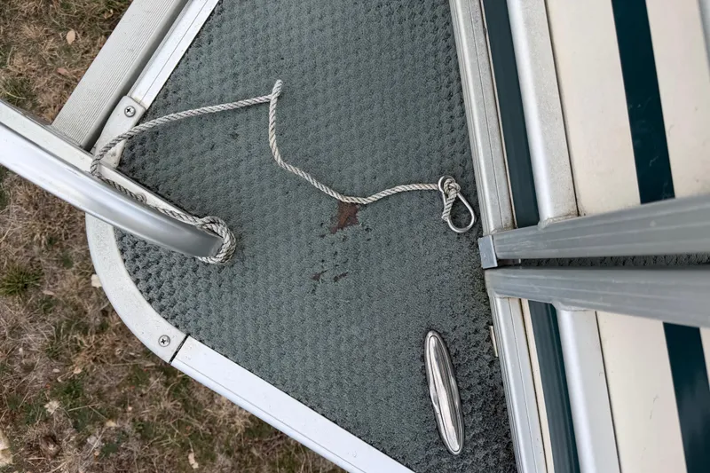 Slide: The Image of 2004 Sanpan 2500 RE boat deck with rope and cleat on textured surface. - 55