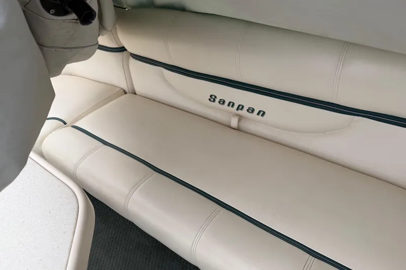 Slide: The Image of 2004 Sanpan 2500 RE boat interior with beige seating and logo detail. - 56