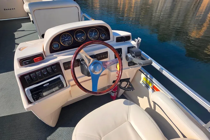 Slide: The Image of 2004 Sanpan 2500 RE boat dashboard with steering wheel and control panel on water. - 6