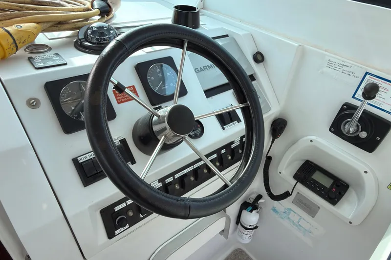 Slide: The Image of 1999 Mainship Pilot 30 interior with white seating and steering wheel, docked at marina. - 11