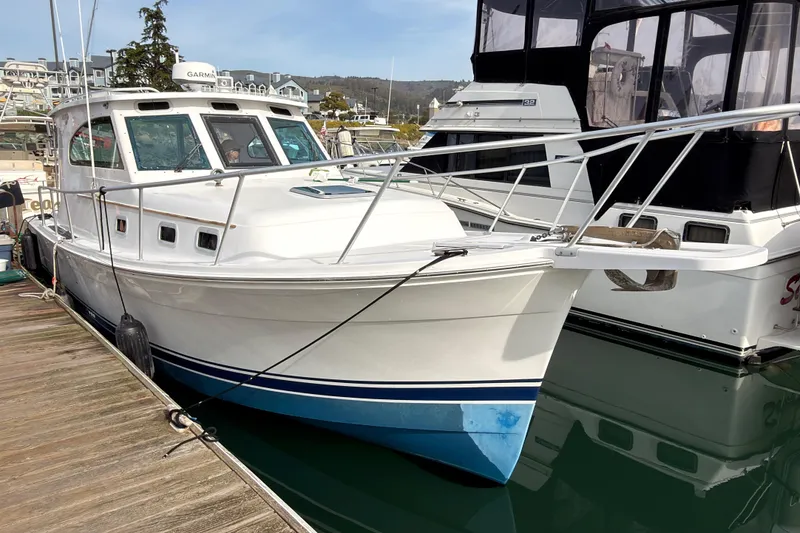 Slide: The Image of 1999 Mainship Pilot 30 docked at marina, white hull with blue accents. - 18