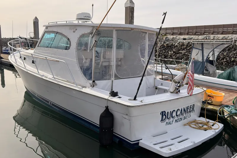 Slide: The Image of 1999 Mainship Pilot 30 boat named "Buccaneer" docked at a marina. - 2