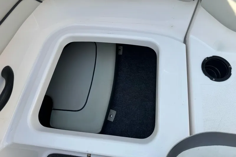 Slide: The Image of 2022 Yamaha Boats SX190 storage compartment with carpeted interior and white finish. - 21