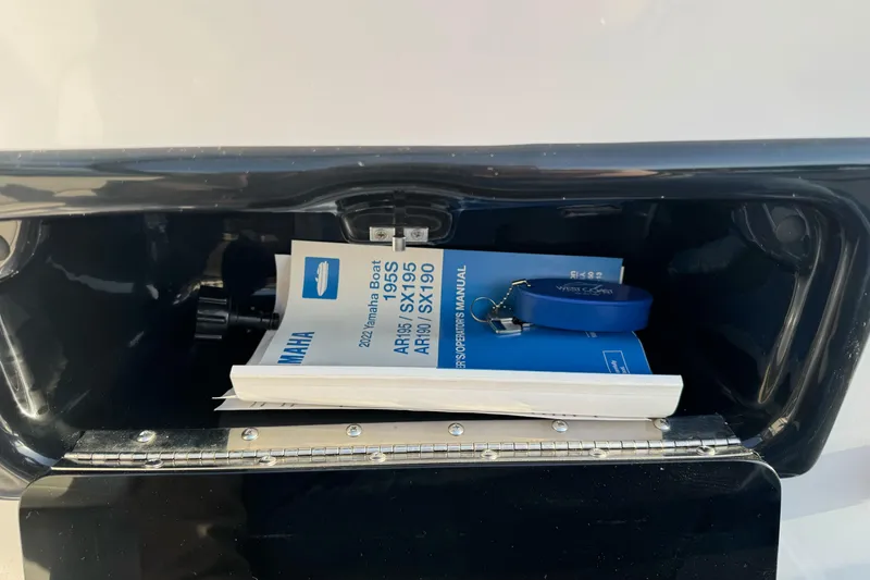Slide: The Image of 2022 Yamaha Boats SX190 manual and keychain in storage compartment. - 23